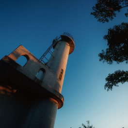 ［08  大村湾を見晴らす田島灯台］田島の頂上に白くそびえる塔が「田島灯台」。昭和44年に建設されました。標高21.5ｍの地にあり、灯台周辺では大村湾をパノラマで見晴らせます。晴れていれば遙か雲仙まで☆